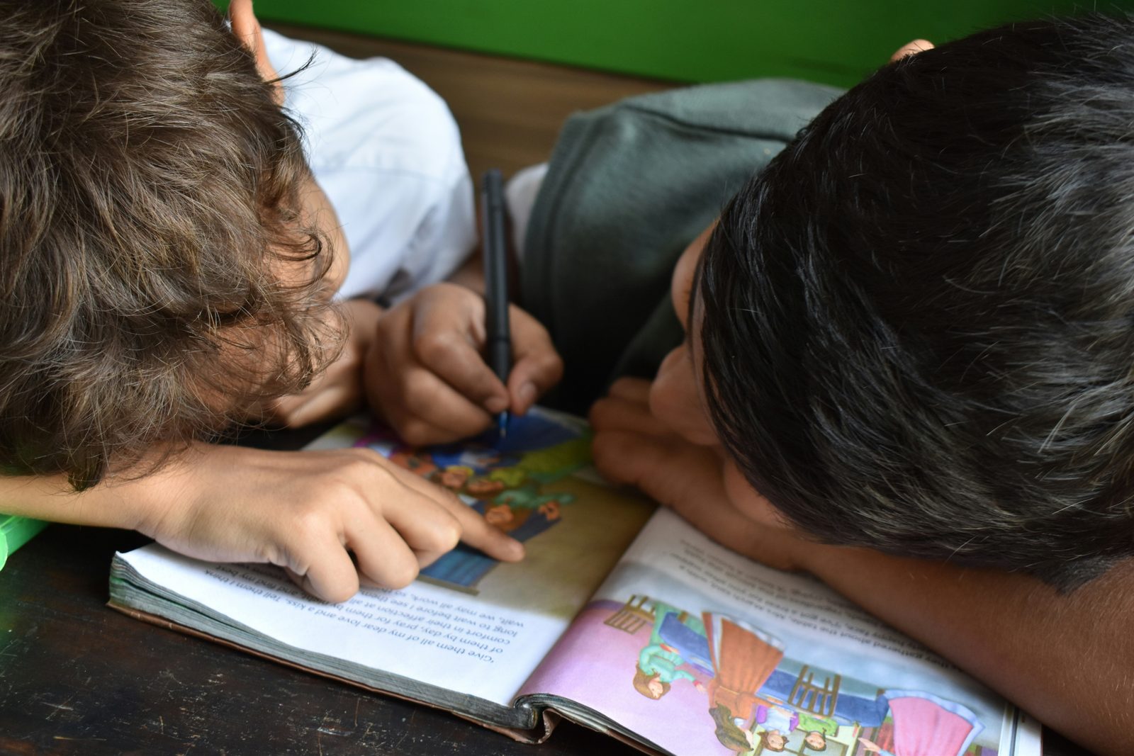 Two children doing schoolwork together at a table at home.